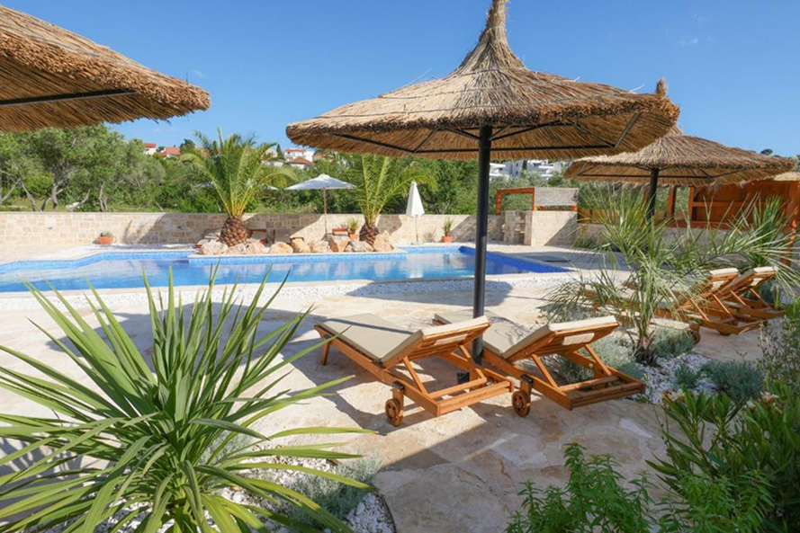 View of Villa Lojena from the outside from the outside during daytime with Pool and Palms
