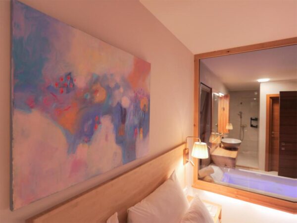 Painting above the bedroom bed illuminateed by a night lamp