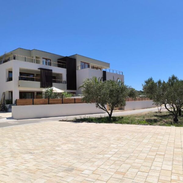 View of the apartment building and tree garden surrounded with paved courtyard