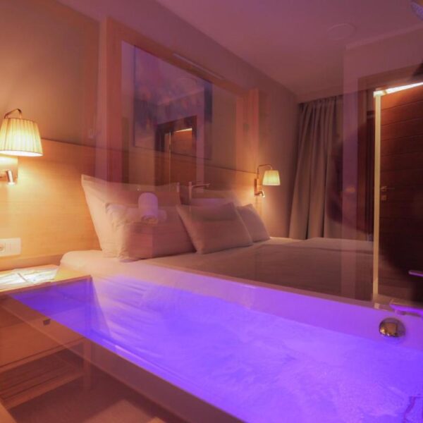 View of illuminated whirlpool bath from window by the bed