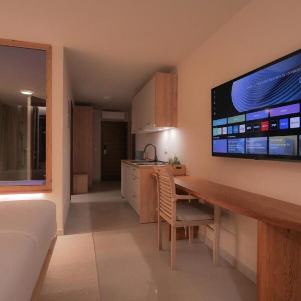 View of white coloured kitchen and big smart tv